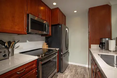 a kitchen with stainless steel appliances and wooden cabinets at Oceanside Beach Condos in Oceanside