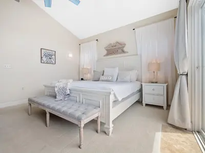 a white bedroom with a white bed and a bench at Luxury beach home one block from ocean with spa, WiFi, & gorgeous outdoor space in San Diego