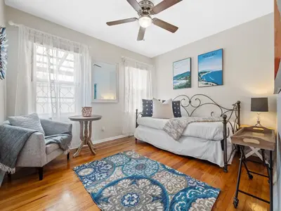 a bedroom with a bed and a chair at Luxury beach home one block from ocean with spa, WiFi, & gorgeous outdoor space in San Diego