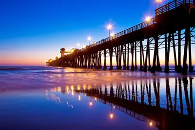 a pier with lights on the beach at night at Oceanside Beach Condos in Oceanside