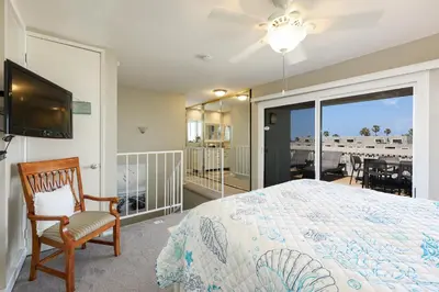 a bedroom with a bed and a tv and a balcony at Oceanside Beach Condos in Oceanside