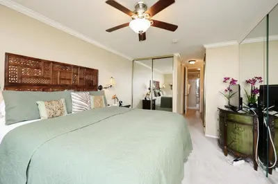a bedroom with a large bed with a ceiling fan at Oceanside Beach Condos in Oceanside