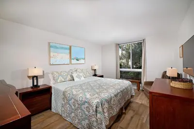 a bedroom with a bed and a desk and a window at Oceanside Beach Condos in Oceanside
