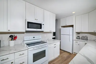 a white kitchen with white appliances and white cabinets at Oceanside Beach Condos in Oceanside