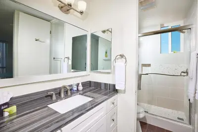 a white bathroom with a sink and a shower at Oceanside Beach Condos in Oceanside