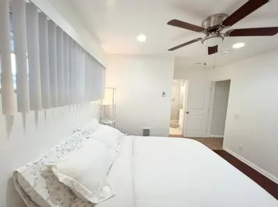 a white bedroom with a bed and a ceiling fan at Historical Beach Bungalow Steps Away From Sand #5 in Newport Beach