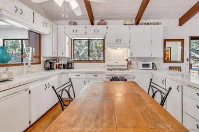 a kitchen with white cabinets and a wooden table at The Bungalow Partial Home Rental in Julian