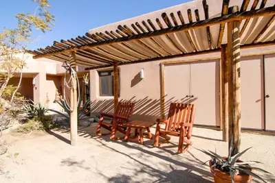 a patio with two chairs and a wooden pergola at Borrego Valley Inn in Borrego Springs