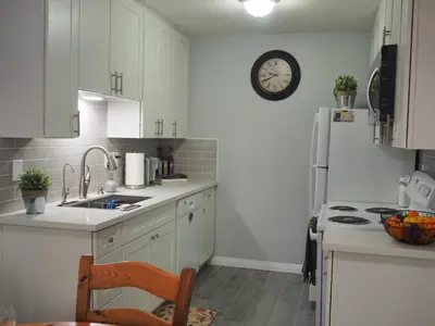a kitchen with white cabinets and a clock on the wall at Charming 1Bedroom Vacation Condo in Oceanside