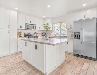 a kitchen with white cabinets and a stainless steel refrigerator at Villa Descanso in Oceanside