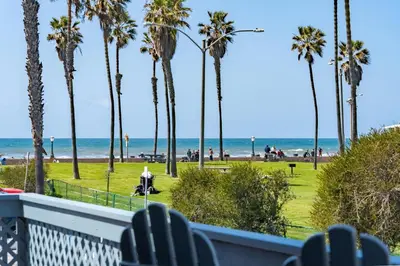 a view of the beach from the balcony of a resort with palm trees at Belmont Ocean Views - Massive Private Deck, Grill & Parking in San Diego
