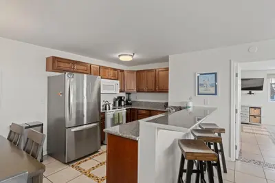 a kitchen with a stainless steel refrigerator and wooden cabinets at Belmont Ocean Views - Massive Private Deck, Grill & Parking in San Diego