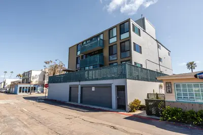 a tall white building with a garage in a street at Belmont Ocean Views - Massive Private Deck, Grill & Parking in San Diego