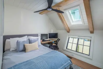 a bedroom with a bed with a ceiling fan and a desk at Neptune Experience in Encinitas