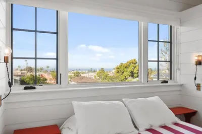 a bedroom with windows and a bed with white pillows at Coastal La Jolla Luxury - AC & Large Ocean View Patio! in San Diego