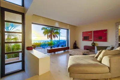 a living room with a couch and a large window at Sunset Cliffs Modern Luxury Estate w Ocean Views, Oversized Spa, AC, Yard! in San Diego