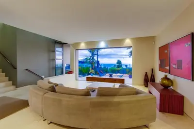a living room with a large couch and a large window at Sunset Cliffs Modern Luxury Estate w Ocean Views, Oversized Spa, AC, Yard! in San Diego