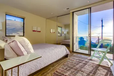 a bedroom with a bed and a chair and a window at Sunset Cliffs Modern Luxury Estate w Ocean Views, Oversized Spa, AC, Yard! in San Diego