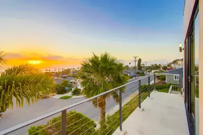 a balcony with a view of the ocean and palm trees at Sunset Cliffs Modern Luxury Estate w Ocean Views, Oversized Spa, AC, Yard! in San Diego