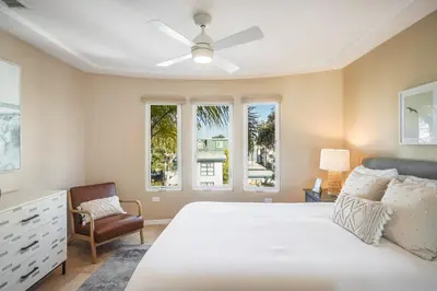 a bedroom with a bed and a chair and windows at Massive Dream Beach Home - Dog Friendly, AC, Steps2Sand in San Diego