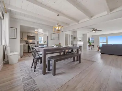 a dining room and living room with a table and chairs at Stunning Oceanfront Villa - Massive Patio, Hot Tub, Parking, Pet Friendly & Views! in San Diego