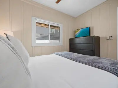 a bedroom with a white bed and a television at Stunning Oceanfront Villa - Massive Patio, Hot Tub, Parking, Pet Friendly & Views! in San Diego