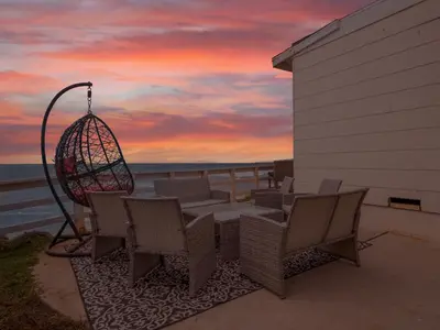 a patio with a table and chairs and a sunset at Stunning Oceanfront Villa - Massive Patio, Hot Tub, Parking, Pet Friendly & Views! in San Diego