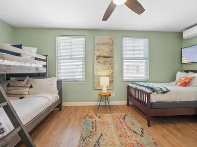 a bedroom with two bunk beds and a couch at Stunning Beach House- Rooftop Patio & Ocean Views in San Diego