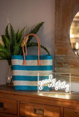 a blue and white striped bag on a dresser with a plant at Oceanfront, two-level condo with stunning view, decks, fast WiFi & fireplace in San Diego
