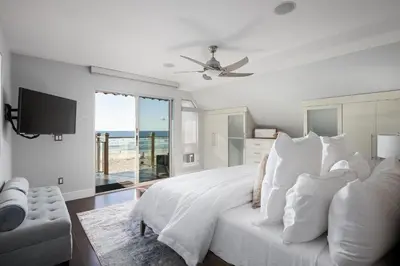 a white bedroom with a bed and a television at Oceanfront, two-level condo with stunning view, decks, fast WiFi & fireplace in San Diego