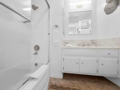 a white bathroom with a shower and a sink at Sunset Cliffs Lookout - Ocean Front Luxury Condo in San Diego