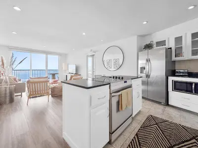 a kitchen with white cabinets and a stainless steel refrigerator at Sunset Cliffs Lookout - Ocean Front Luxury Condo in San Diego