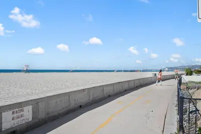 a woman walking down a sidewalk next to the beach at Mission Paradise - Spa, Pet Friendly, Steps2Sand in San Diego