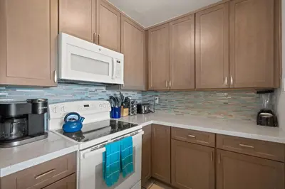 a kitchen with wooden cabinets and a white stove top oven at Belmont Modern - Ocean View, Pet Friendly, Patio in San Diego