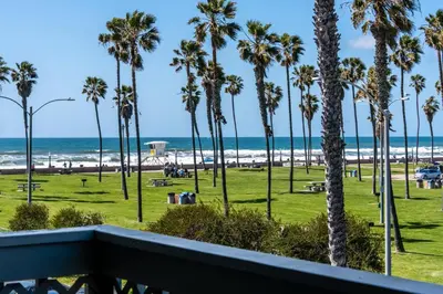 a view of the beach from a balcony with palm trees at Belmont Modern - Ocean View, Pet Friendly, Patio in San Diego