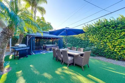 a patio with a table and chairs and an umbrella at Shores Perfection - Spa, AC, Pet Friendly, Parking, Fire Pit & Massive Private Yard! in San Diego