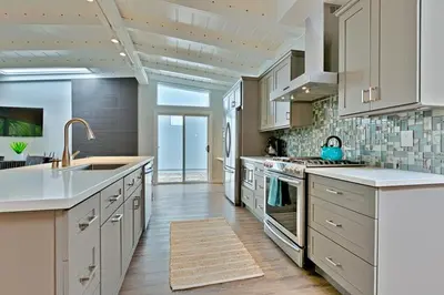 a large kitchen with white cabinets and a sink at Shores Perfection - Spa, AC, Pet Friendly, Parking, Fire Pit & Massive Private Yard! in San Diego