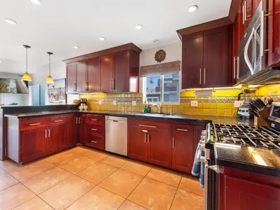 a large kitchen with wooden cabinets and appliances at Ocean View Beach Haven! Steps2Beach & Pet Friendly in San Diego