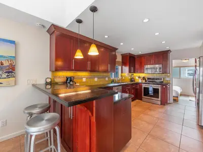 a kitchen with wooden cabinets and a counter top at Ocean View Beach Haven! Steps2Beach & Pet Friendly in San Diego