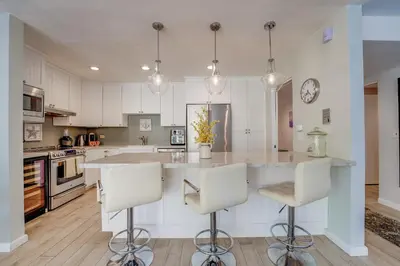 a kitchen with white cabinets and a large island with bar stools at Bayfront Paradise - Flexible 30 Day plus w Amazing Bay View and Pool in San Diego
