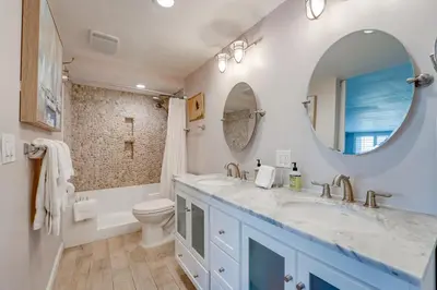 a bathroom with two sinks and a toilet and a mirror at Bayfront Paradise - Flexible 30 Day plus w Amazing Bay View and Pool in San Diego