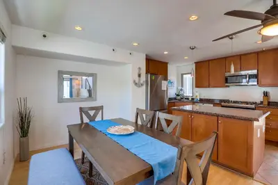a kitchen with a wooden table and a dining room at Beach Oasis - Rooftop, Steps2Sand and Water Views in San Diego