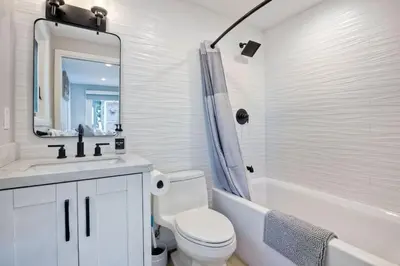 a white bathroom with a toilet and a sink and a mirror at Luxury Ocean Oasis 3BR I Balcony I Firepit in San Diego