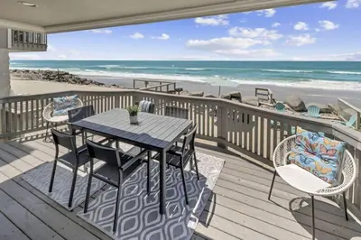 a deck with a table and chairs and the beach at Oceanfront Home with Stunning View in Oceanside
