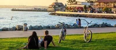 a group of people sitting on the grass by the water at Bay Views & Gaslamp/Little Italy/Convention 1BD in San Diego