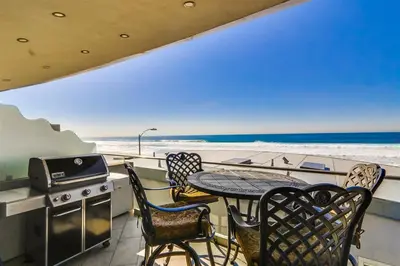 a balcony with a table and chairs and the beach at Ocean view, two-level condo with stunning view, decks, fast WiFi & fireplace in San Diego