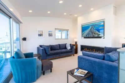 a living room with blue couches and a fireplace at Ocean view, two-level condo with stunning view, decks, fast WiFi & fireplace in San Diego