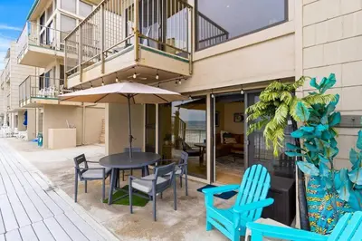 a table with chairs and an umbrella in front of a building at A Wave From It All in Carlsbad