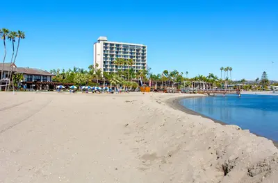 a view of a beach with a building in the background at Mission Bay Cottage - Bay View Patio, Parking, WasherDryer in San Diego