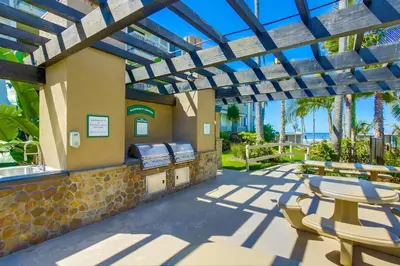 a patio with a grill and tables and chairs at Brooks Beach Vacations Villa C205 Oceanside in Oceanside